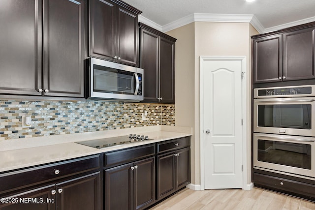 kitchen featuring stainless steel appliances, light countertops, ornamental molding, and tasteful backsplash