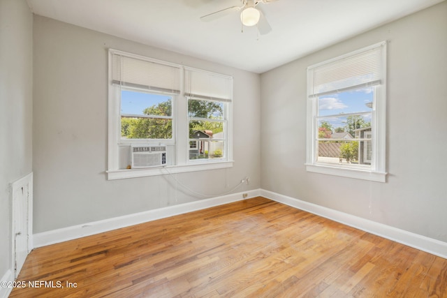 empty room featuring cooling unit, light hardwood / wood-style flooring, and ceiling fan