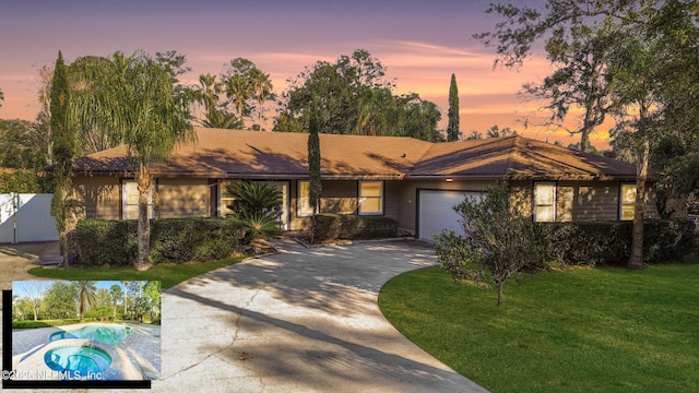 view of front facade featuring a garage, driveway, a front lawn, and a pool with connected hot tub