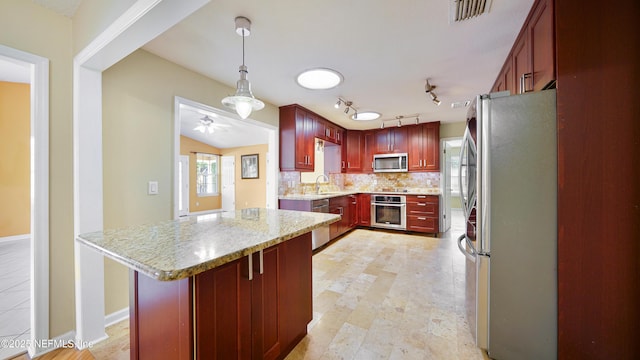 kitchen with reddish brown cabinets, stainless steel appliances, visible vents, decorative backsplash, and a sink