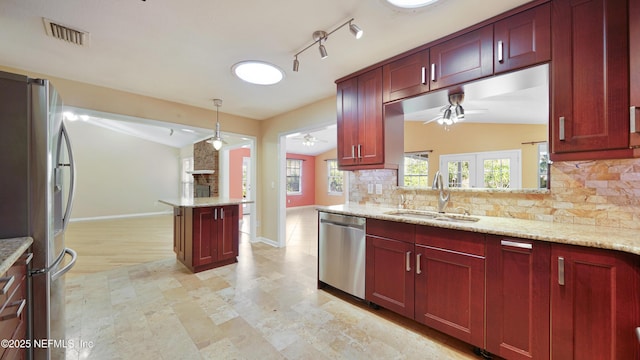 kitchen with reddish brown cabinets, visible vents, decorative backsplash, appliances with stainless steel finishes, and a sink