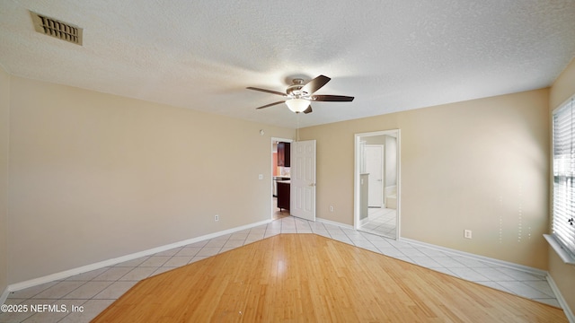 unfurnished room with baseboards, visible vents, ceiling fan, a textured ceiling, and light tile patterned flooring