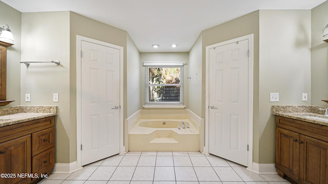 full bath featuring tile patterned flooring, two vanities, baseboards, and a bath