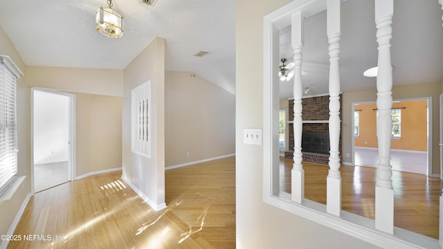 corridor featuring lofted ceiling, baseboards, and wood finished floors