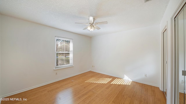 unfurnished room featuring light wood-type flooring, a textured ceiling, baseboards, and a ceiling fan