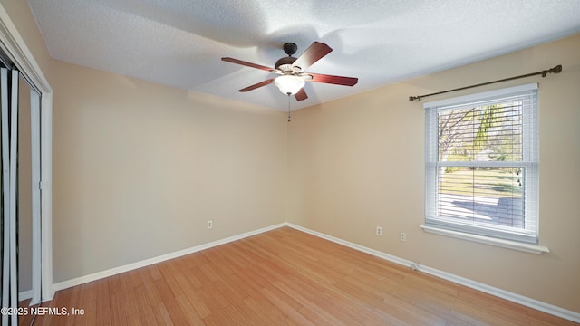 unfurnished room featuring light wood-type flooring, ceiling fan, a textured ceiling, and baseboards