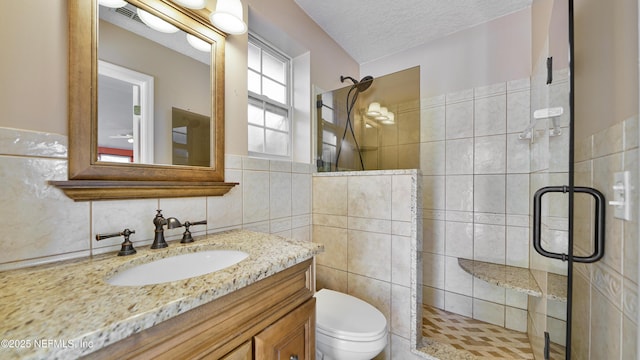 bathroom featuring a textured ceiling, toilet, vanity, tile walls, and a shower stall