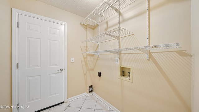 laundry area featuring hookup for a washing machine, electric dryer hookup, a textured ceiling, laundry area, and tile patterned floors