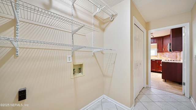 washroom featuring hookup for a washing machine, laundry area, baseboards, and light tile patterned floors