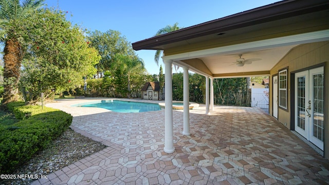 view of pool with a patio, a fenced backyard, ceiling fan, an outbuilding, and french doors