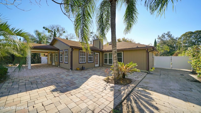 rear view of house with a chimney, fence, and a gate