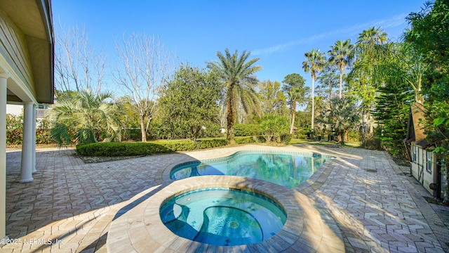 outdoor pool with a patio area and an in ground hot tub