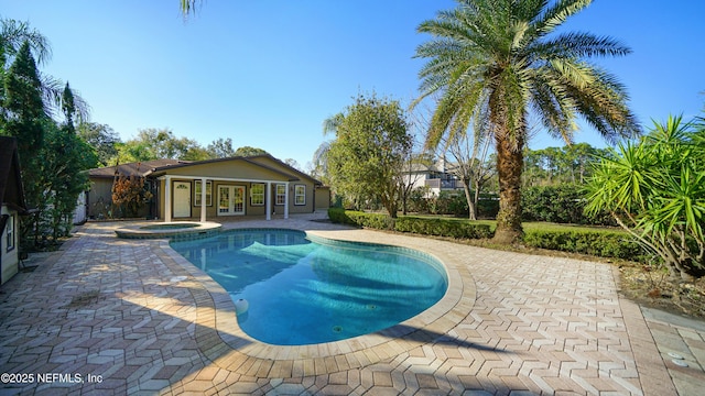 view of swimming pool with french doors, a patio area, and a pool with connected hot tub