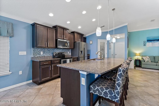 kitchen featuring dark stone countertops, sink, appliances with stainless steel finishes, a kitchen breakfast bar, and pendant lighting