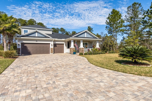 view of front of home with a garage, covered porch, and a front yard