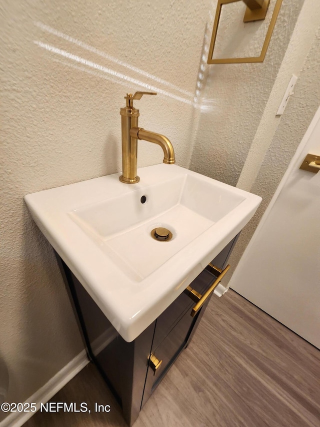 details with a textured wall, a sink, and wood finished floors