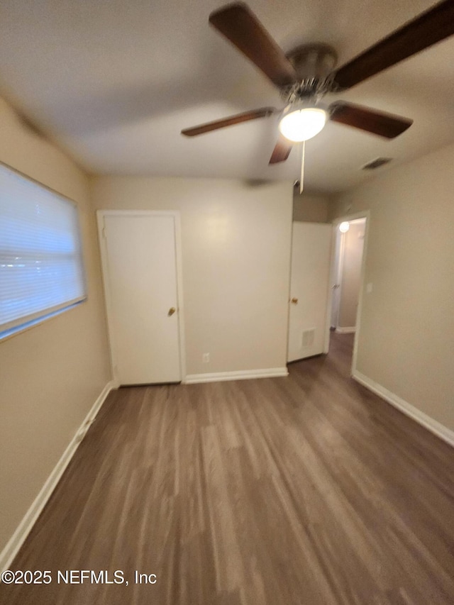 empty room with wood finished floors, visible vents, and baseboards