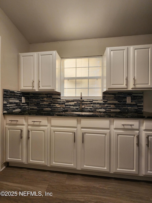 kitchen with lofted ceiling, dark wood-style floors, white cabinets, and backsplash