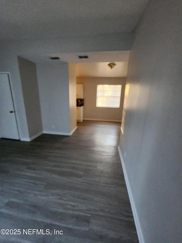 corridor with baseboards, visible vents, and wood finished floors