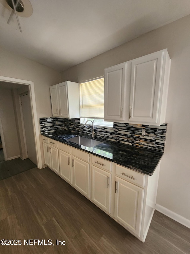 kitchen featuring dark wood-style floors, tasteful backsplash, white cabinets, and a sink