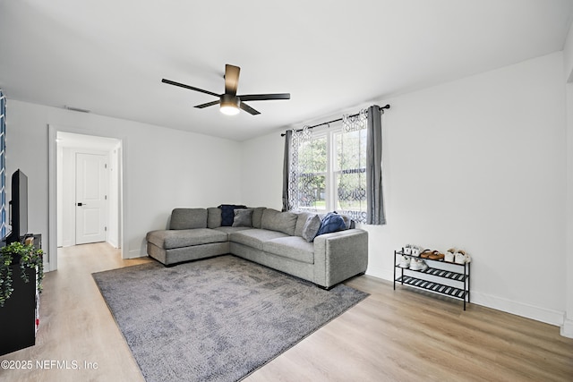 living area with light wood finished floors, baseboards, and a ceiling fan