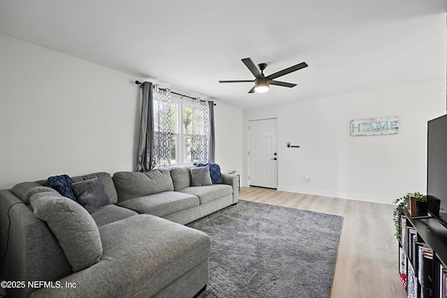 living area with light wood-style floors, baseboards, and a ceiling fan