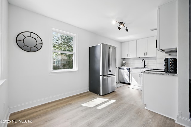 kitchen featuring baseboards, decorative backsplash, light wood-style flooring, appliances with stainless steel finishes, and white cabinetry