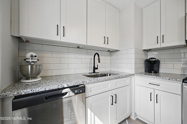 kitchen with a sink, backsplash, white cabinets, and stainless steel dishwasher