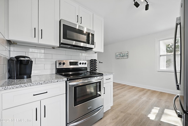 kitchen featuring stainless steel appliances, backsplash, light wood finished floors, and light stone countertops