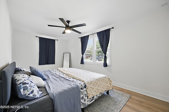 bedroom with ceiling fan, baseboards, and wood finished floors