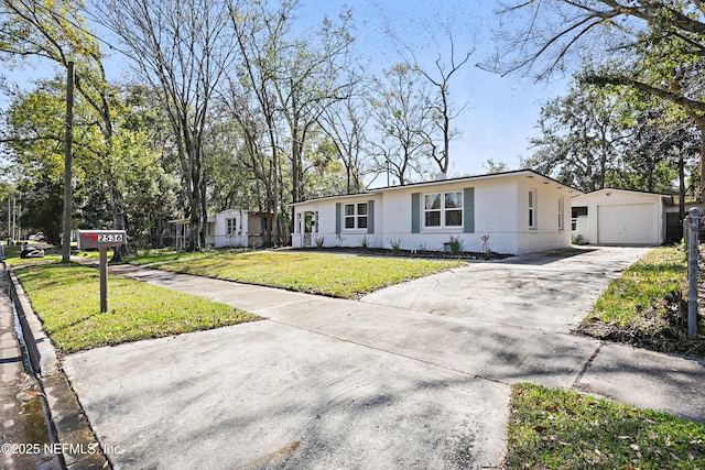 view of front of property featuring driveway, a detached garage, a front yard, and an outdoor structure