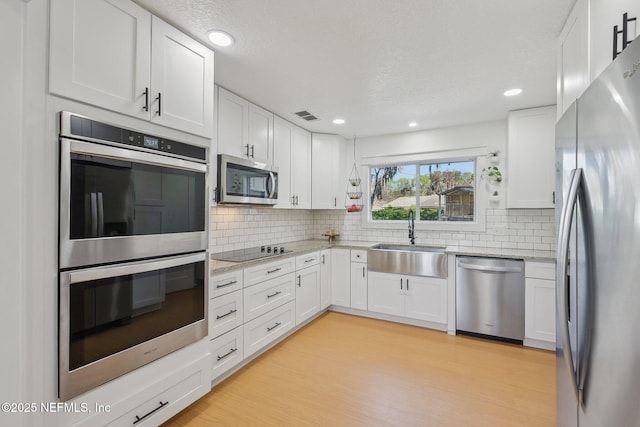 kitchen featuring a sink, white cabinets, visible vents, and stainless steel appliances