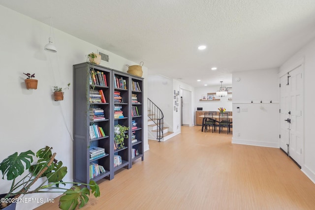 corridor featuring light wood-type flooring, visible vents, a textured ceiling, recessed lighting, and stairway