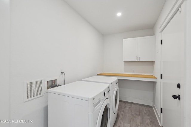 clothes washing area with light wood finished floors, visible vents, baseboards, cabinet space, and washer and dryer