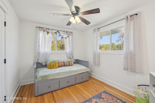 bedroom with ceiling fan, baseboards, and wood finished floors