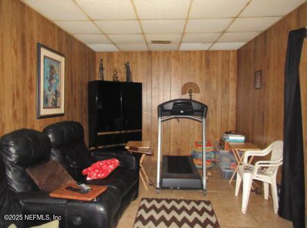 interior space with a drop ceiling and wood walls