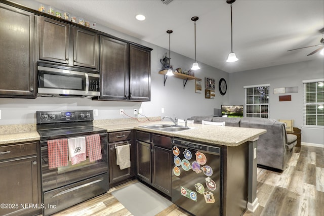 kitchen featuring pendant lighting, light countertops, open floor plan, a sink, and black appliances