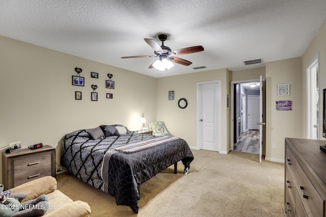 bedroom featuring light carpet, baseboards, visible vents, and a textured ceiling