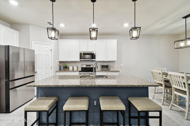 kitchen featuring white cabinetry, a center island with sink, sink, and stainless steel appliances