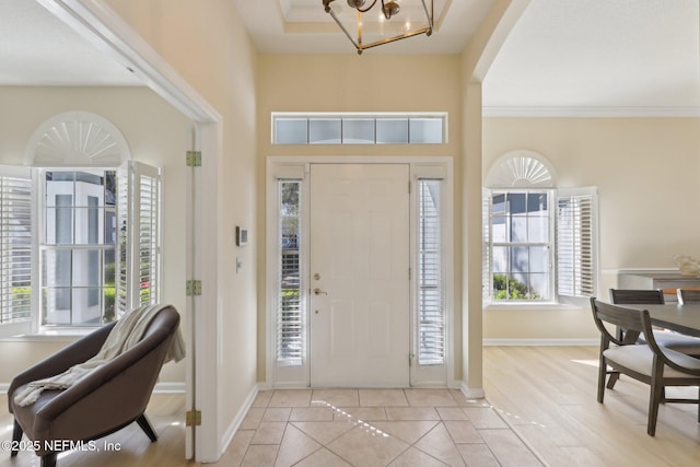 tiled foyer featuring crown molding and a notable chandelier