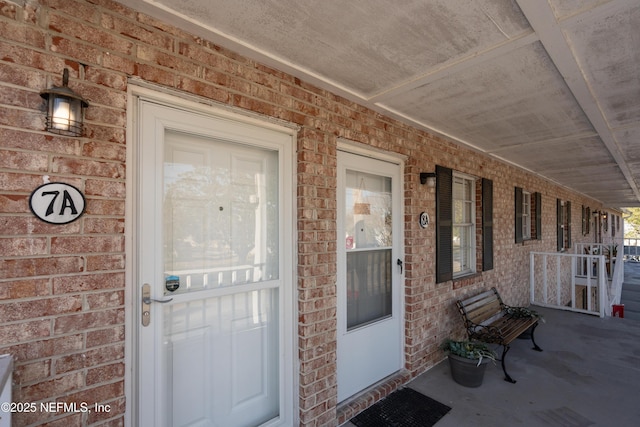 property entrance featuring covered porch and brick siding