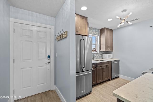 kitchen featuring a sink, visible vents, light wood-style floors, light countertops, and appliances with stainless steel finishes