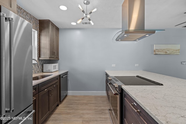 kitchen with visible vents, light wood-style flooring, island exhaust hood, stainless steel appliances, and a sink