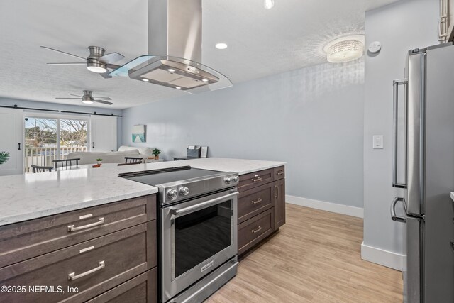 kitchen featuring a barn door, dark brown cabinets, appliances with stainless steel finishes, light wood-type flooring, and island exhaust hood