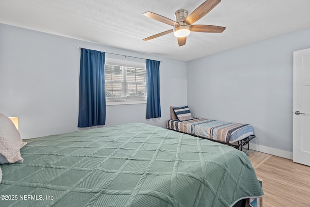 bedroom featuring a ceiling fan, baseboards, and wood finished floors