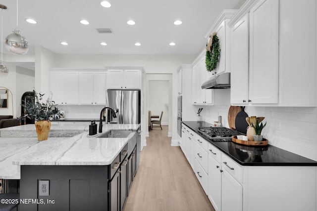 78 Cameron Dr, Ponte Vedra, FL 32081 - kitchen with under cabinet range hood, white cabinetry, pendant lighting, and dark stone counters