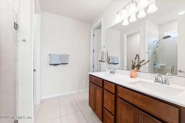 full bathroom with a tile shower, tile patterned floors, double vanity, and a sink