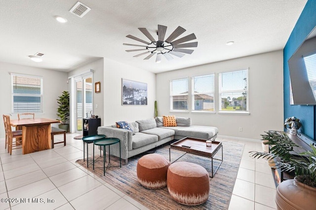 living room featuring light tile patterned floors, baseboards, visible vents, and a textured ceiling