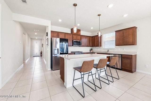 kitchen featuring a breakfast bar area, a kitchen island, hanging light fixtures, light countertops, and appliances with stainless steel finishes