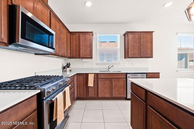 kitchen with light tile patterned floors, a sink, stainless steel appliances, light countertops, and a textured ceiling